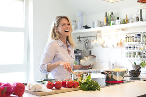 Glückliche Frau beim Kochen in der Küche - MAEF010119