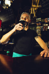 Kellner trinkt Bier in einem irischen Pub - MBEF001391