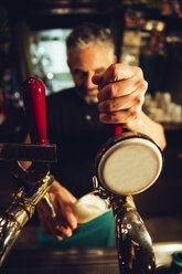 Hand eines Mannes beim Bierzapfen in einem irischen Pub - MBEF001379