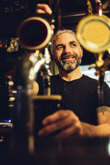 Mann zapft Bier in einem irischen Pub - MBEF001380