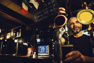 Mann zapft Bier in einem irischen Pub - MBEF001394