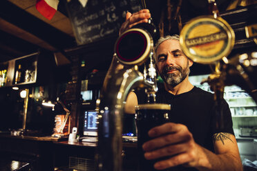 Mann zapft Bier in einem irischen Pub - MBEF001395