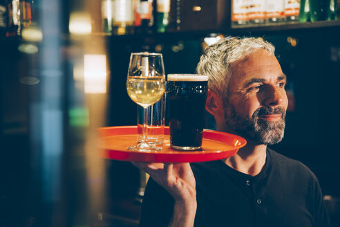 Waiter holding traywith beverages in an Irish pub - MBEF001385