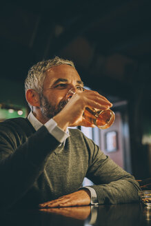 Mann sitzt am Tresen einer Kneipe und trinkt Bier - MBEF001366