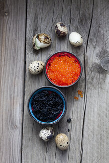 Schwarzer und roter Kaviar in Schalen, gekochte Wachteleier auf Holz - CSF025127
