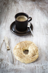 Frühstück, selbstgebackener Bagel, Kaffeetasse und Messer auf Holz - EVGF001432