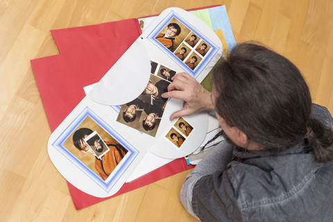 Mann liegt auf dem Boden und sieht sich Bilder aus seiner Kindheit an, lizenzfreies Stockfoto