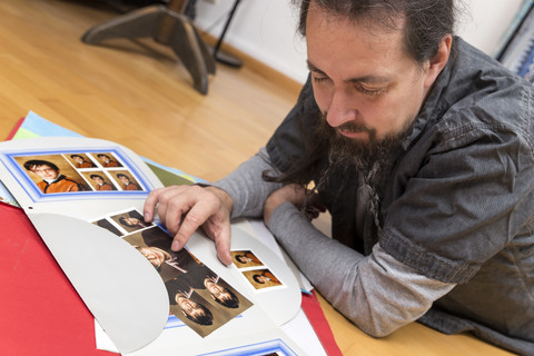 Mann liegt auf dem Boden und sieht sich Bilder aus seiner Kindheit an, lizenzfreies Stockfoto