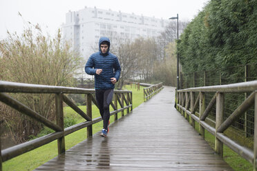 Spain, Galicia, Naron, runner on a promenade in park at a rainy day - RAEF000121