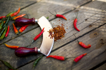 Red and green chili pods, mezzaluna and chili powder on wood - SARF001586