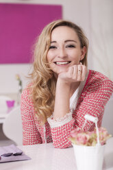 Porträt einer lächelnden blonden Frau, die in einem Café sitzt - JUNF000272