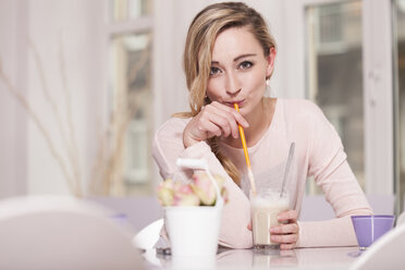 Portrait of blond woman sitting in a coffee shop drinking Latte Macchiato - JUNF000279