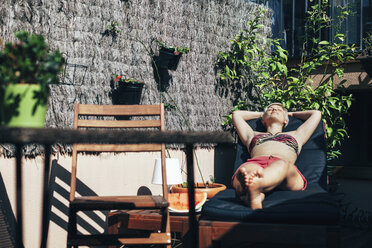 Junge Frau beim Sonnenbaden im Liegestuhl auf ihrer Terrasse - EBSF000467
