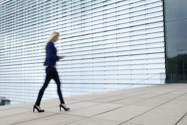 Businesswoman walking with digital tablet - BFRF001037