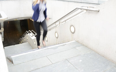 Telefonierende Geschäftsfrau läuft eine Treppe hinauf - BFRF001060