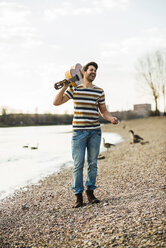 Man standing by the riverside, holding guitar - UUF003743