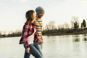 Happy young couple at the riverside walking hand in hand - UUF003753