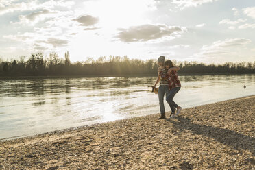 Happy young couple walking at the riverside - UUF003755