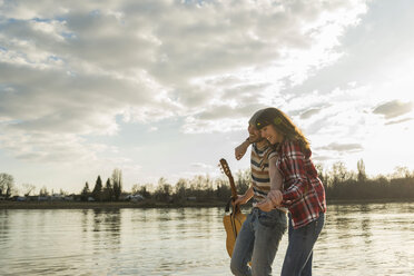 Glückliches junges Paar bei einem Spaziergang am Flussufer - UUF003756