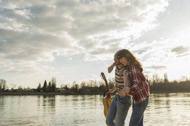 Happy young couple walking at the riverside - UUF003756