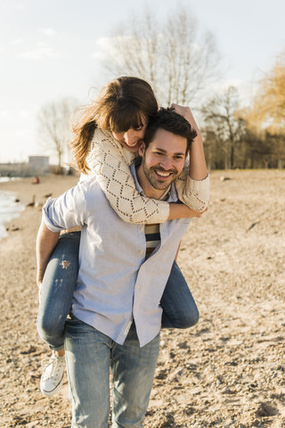 Glückliches junges Paar, das sich am Ufer des Flusses amüsiert, lizenzfreies Stockfoto