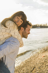 Glückliches junges Paar, das sich am Ufer des Flusses amüsiert - UUF003763