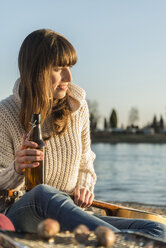 Junge Frau am Flussufer bei einem Bier - UUF003773