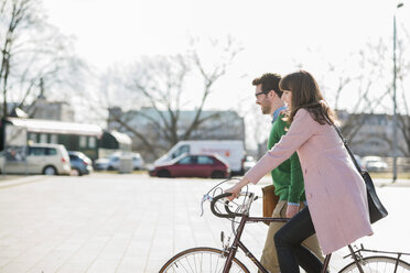 Happy couple going home together, woman riding bicycle - UUF003804