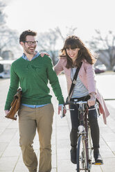Happy couple going home together, woman riding bicycle - UUF003806