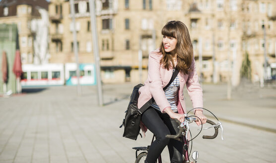 Junge Frau mit Fahrrad in der Stadt - UUF003807