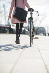 Junge Frau mit Fahrrad in der Stadt - UUF003810
