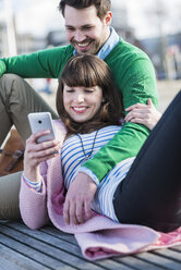 Happy couple resting on bench - UUF003821