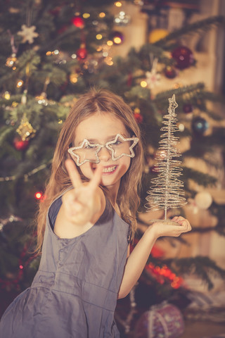 Porträt eines glücklichen kleinen Mädchens vor einem Weihnachtsbaum, lizenzfreies Stockfoto