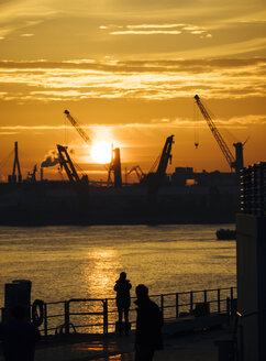 Deutschland, Hamburg, Silhouetten von Hafenkränen bei Sonnenuntergang, im Hintergrund die Köhlbrandbrücke - KRPF001410