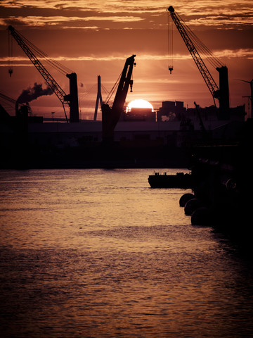 Deutschland, Hamburg, Silhouetten von Hafenkränen bei Sonnenuntergang, im Hintergrund die Köhlbrandbrücke, lizenzfreies Stockfoto