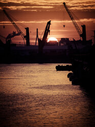 Deutschland, Hamburg, Silhouetten von Hafenkränen bei Sonnenuntergang, im Hintergrund die Köhlbrandbrücke - KRPF001411