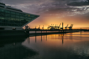 Deutschland, Hamburg, Altona, Bürogebäude Dockland bei Sonnenuntergang, Hamburger Hafen mit Hafenkränen im Hintergrund - KRPF001419