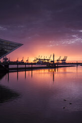 Deutschland, Hamburg, Altona, Bürogebäude Dockland bei Sonnenuntergang, Hamburger Hafen mit Hafenkränen im Hintergrund - KRPF001420