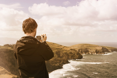 Portugal, Azoren, Mann beim Fotografieren einer Küstenlandschaft, lizenzfreies Stockfoto