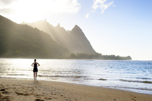 USA, Hawaii, Hanalei, woman standing on Haena Beach, View to Na Pali Coast in the evening light - BRF001115