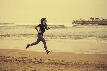 Spanien, Gijon, Frau beim Joggen am Strand - MGOF000189