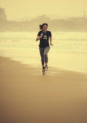 Spain, Gijon, Woman jogging at the beach - MGOF000192