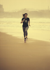 Spanien, Gijon, Frau beim Joggen am Strand - MGOF000192