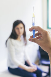 Doctor preparing a syringe with patient in the background - BZF000107