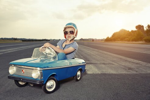 Junge mit Sonnenbrille in Tretauto auf Rennstrecke - EDF000169