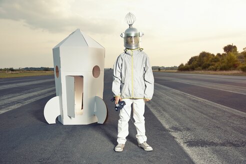 Als Raumfahrer verkleideter Junge steht vor einer Rakete aus Pappe - EDF000144