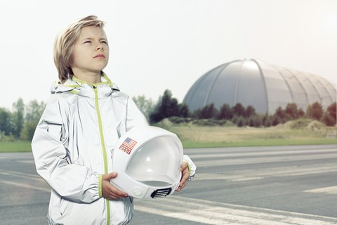 Als Raumfahrer verkleideter Junge schaut nach oben, lizenzfreies Stockfoto
