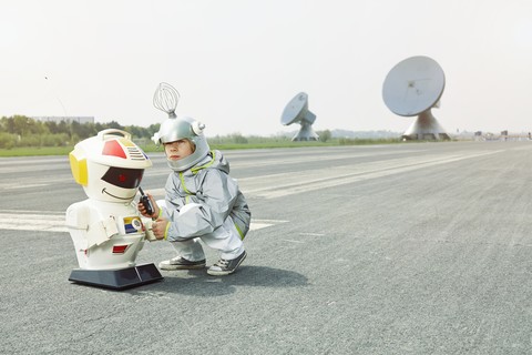 Junge verkleidet als Raumfahrer mit Roboter, lizenzfreies Stockfoto