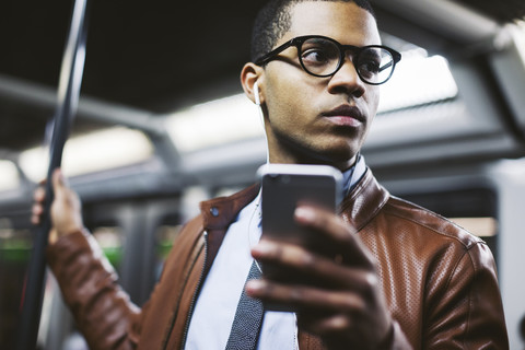 Geschäftsmann mit Smartphone in der U-Bahn, lizenzfreies Stockfoto