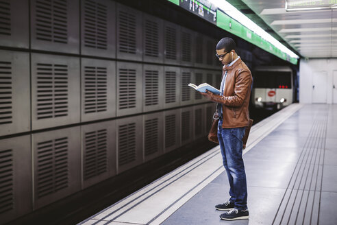 Spanien, Barcelona, Geschäftsmann steht auf dem Bahnsteig einer U-Bahn-Station und liest ein Buch - EBSF000499